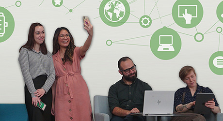 four smiling people with devices.